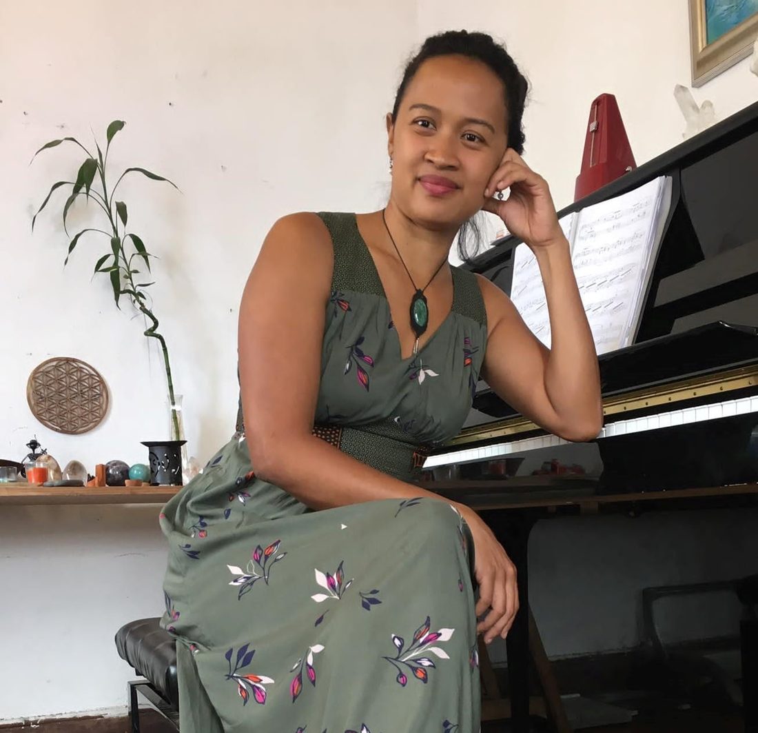 Valérie Raveloson assise à son piano à queue, chez elle.