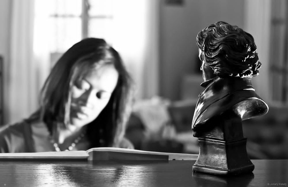 Valérie Raveloson lisant une partition, un buste de Beethoven au premier plan.